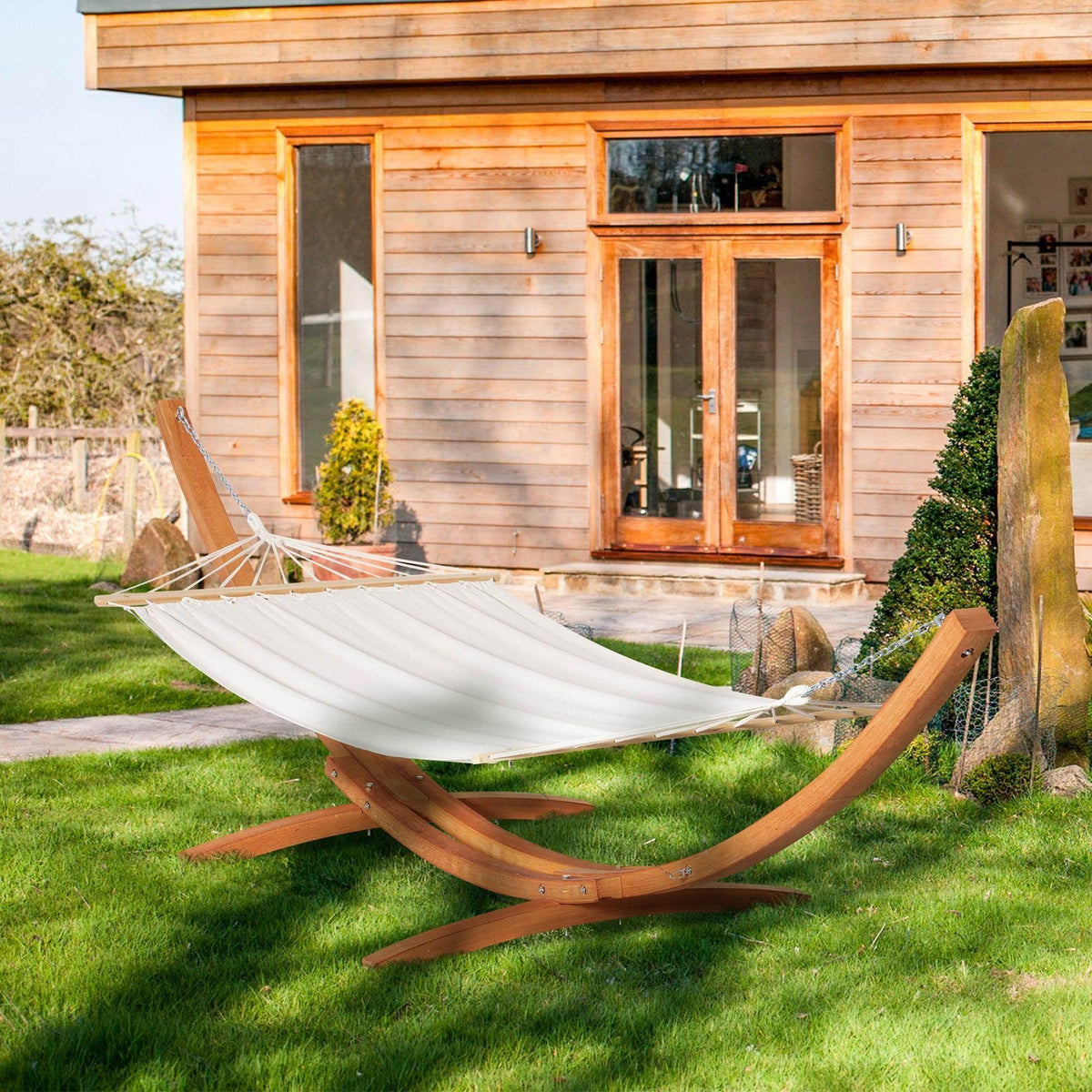 White hammock bed with arched wooden stand and suspended cotton fabric on chains