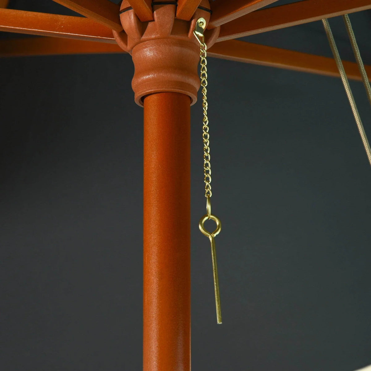 Wooden umbrella pole top with gold chain pull and hanging rope