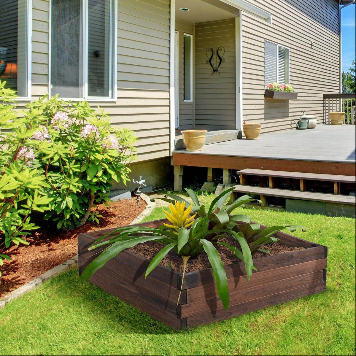 Dark brown wooden raised planter bed with visible soil and green plants in an outdoor yard
