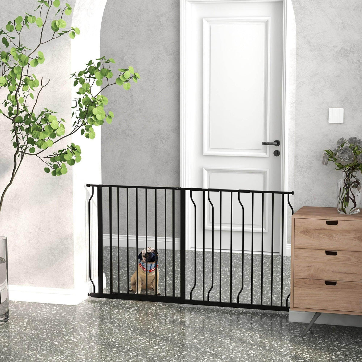 Black metal dog safety gate with vertical bars, freestanding on indoor floor