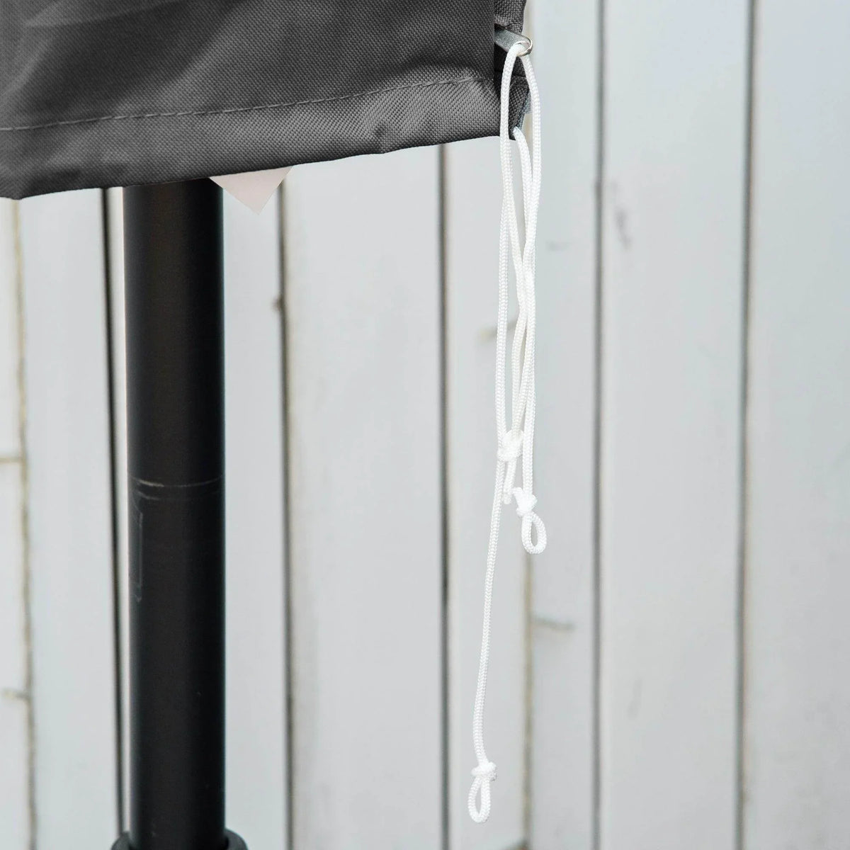 Grey umbrella cover hem with white drawstring cord and grommet on support pole