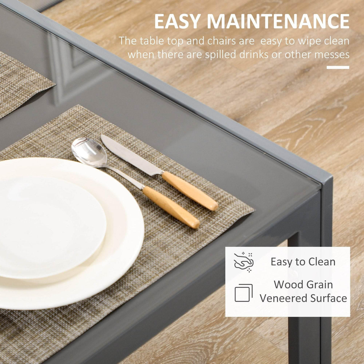 Grey table with smoky glass top and metal frame, with placemat and cutlery