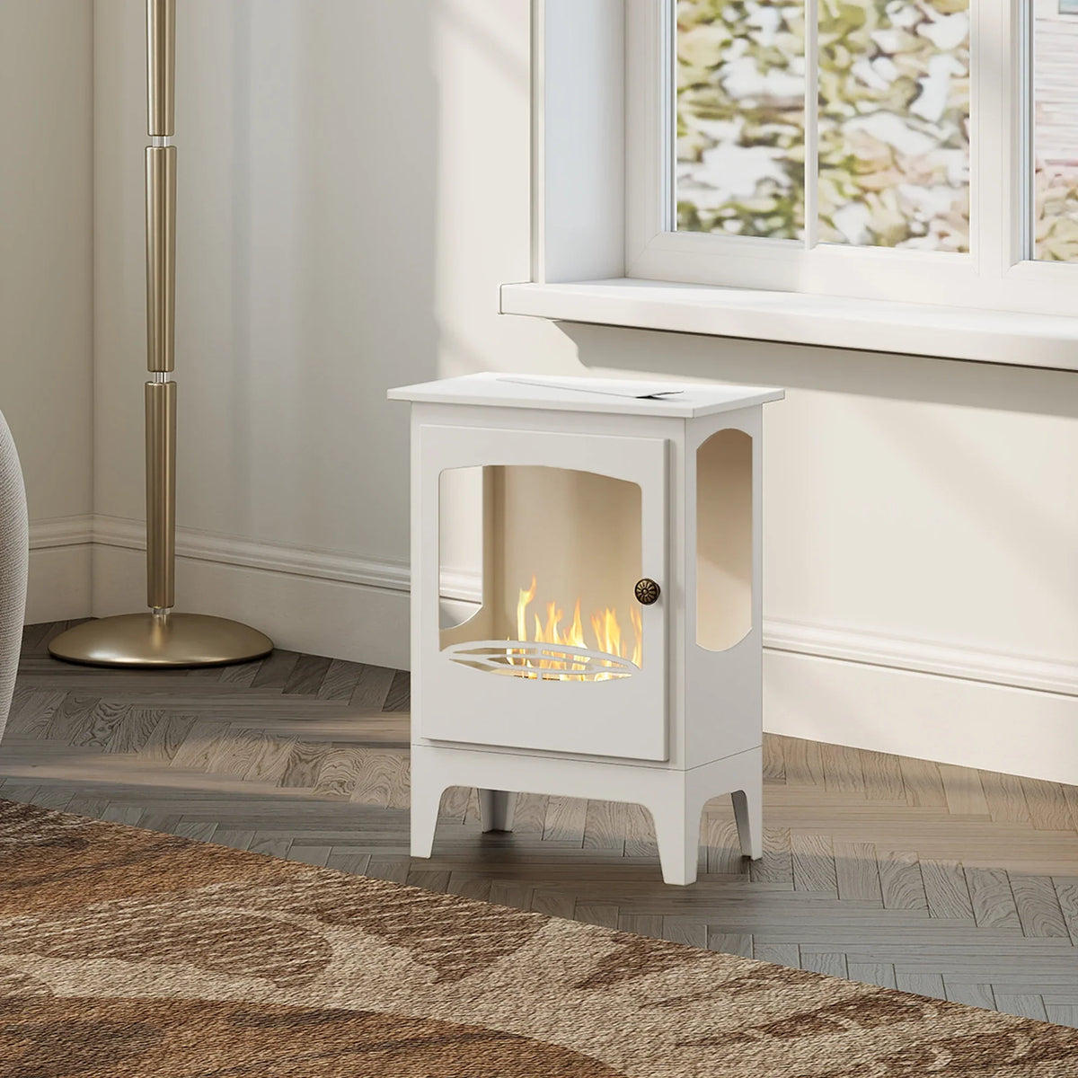 White freestanding ethanol fireplace with burning flames behind front window in a bright room.