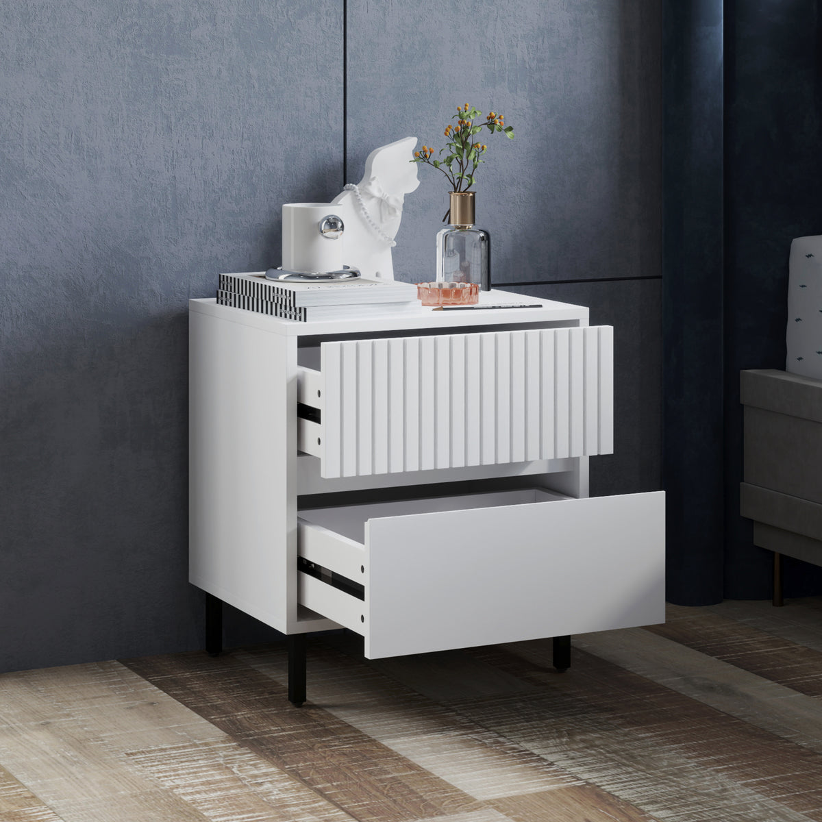 White nightstand with ribbed front panel and partially open bottom drawer