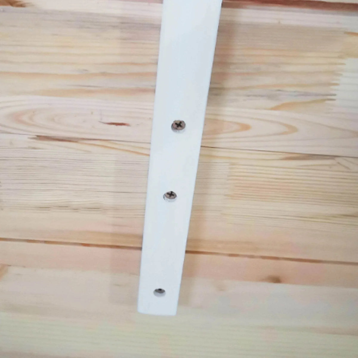 Dining table leg and pine wood tabletop corner with visible screws on white support