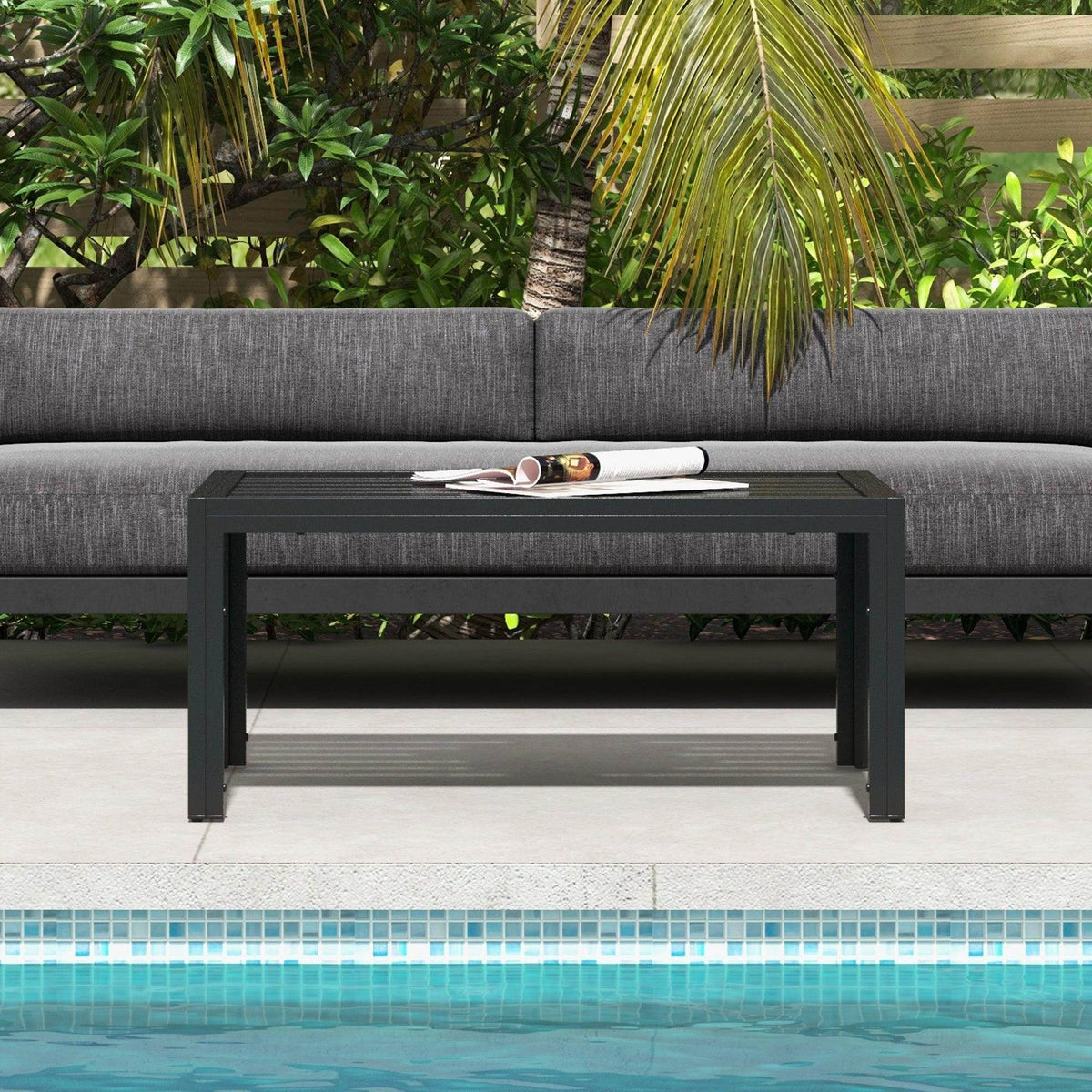 Black patio side table with slat tabletop beside outdoor seating and pool