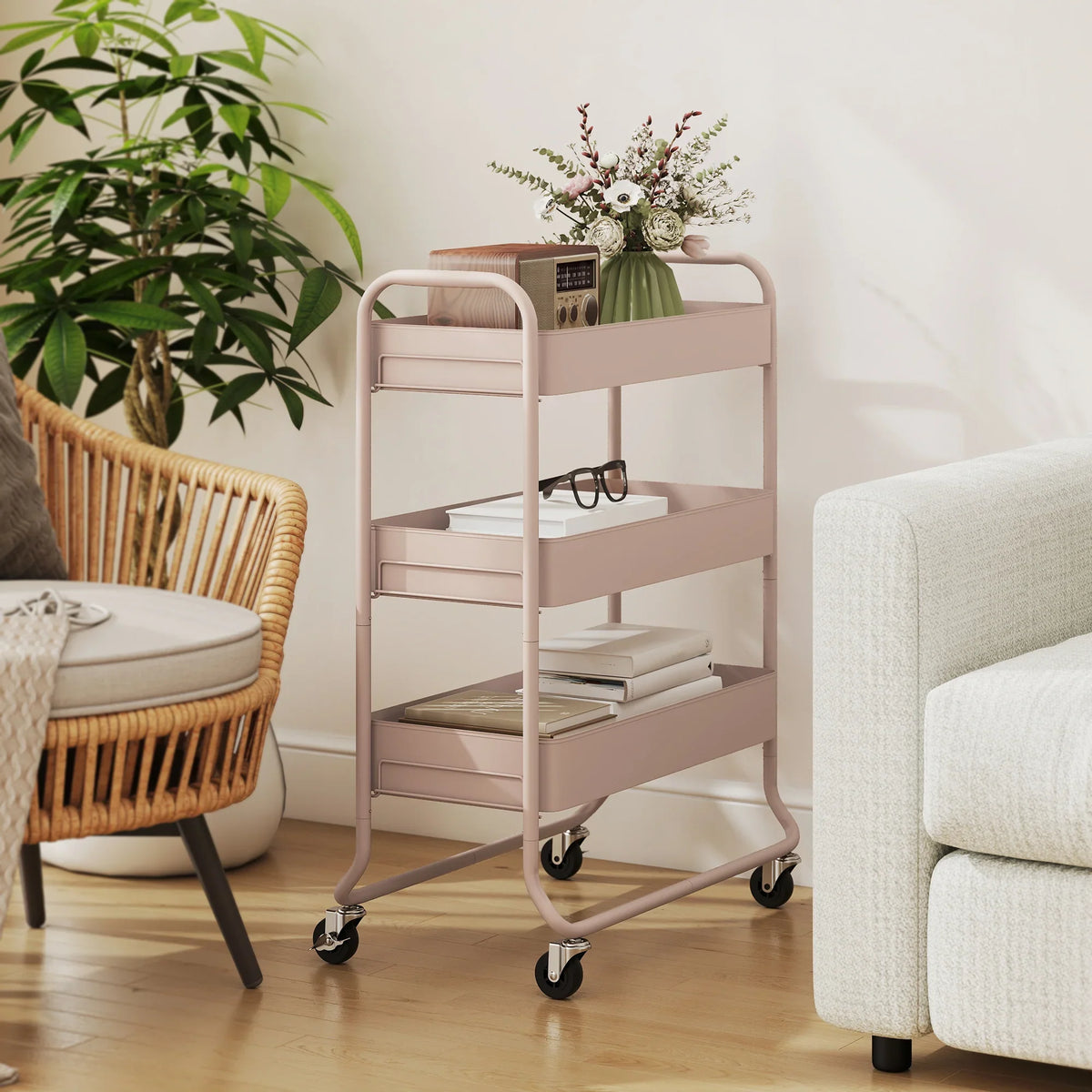 Light pink 3-tier storage trolley with mesh baskets and caster wheels beside a sofa