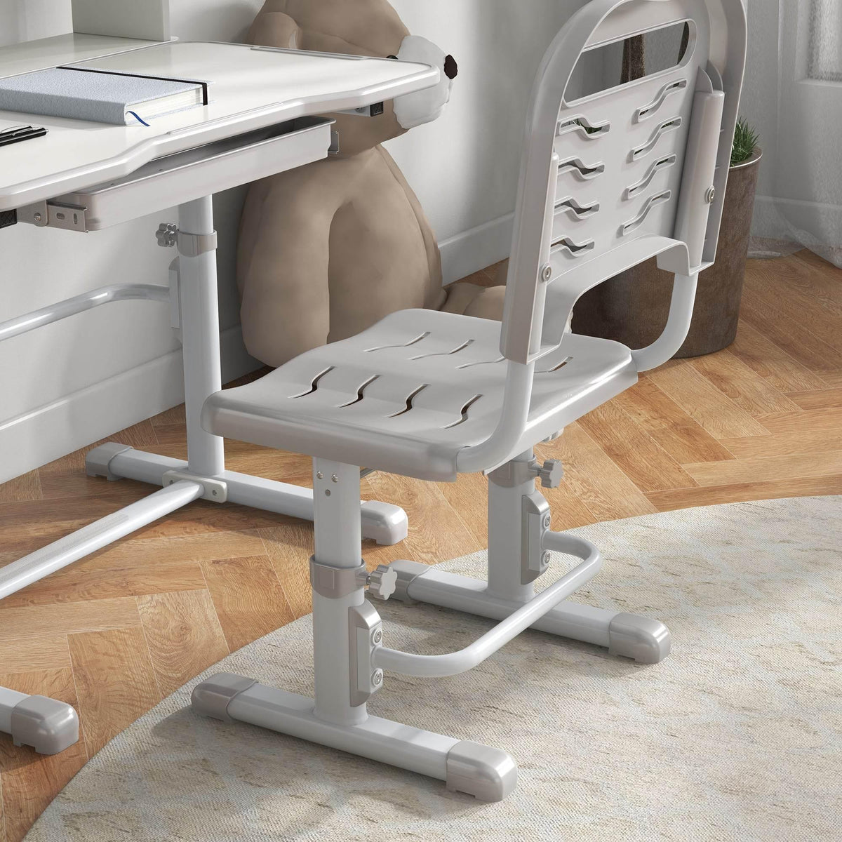 Grey kids study chair with cushioned seat and adjustable height near desk