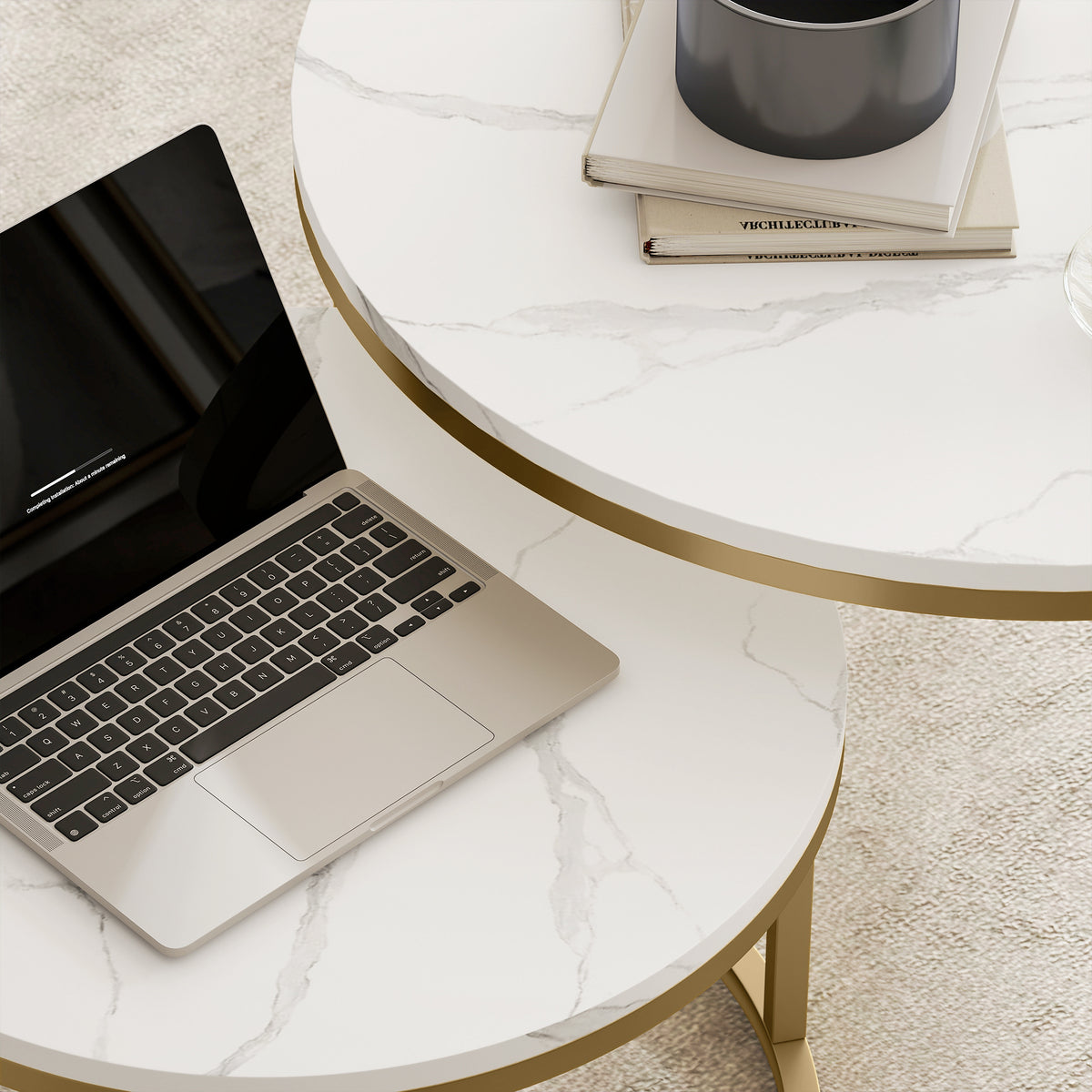 Round marble-look nesting coffee table with gold frame, laptop on top