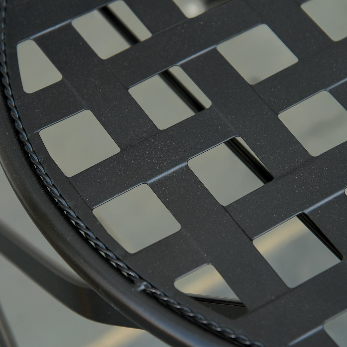 Close-up of black chair seat with woven square cutout pattern