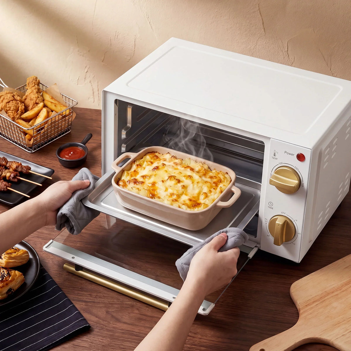 White mini toaster oven with open door, baking dish inside and front knob controls