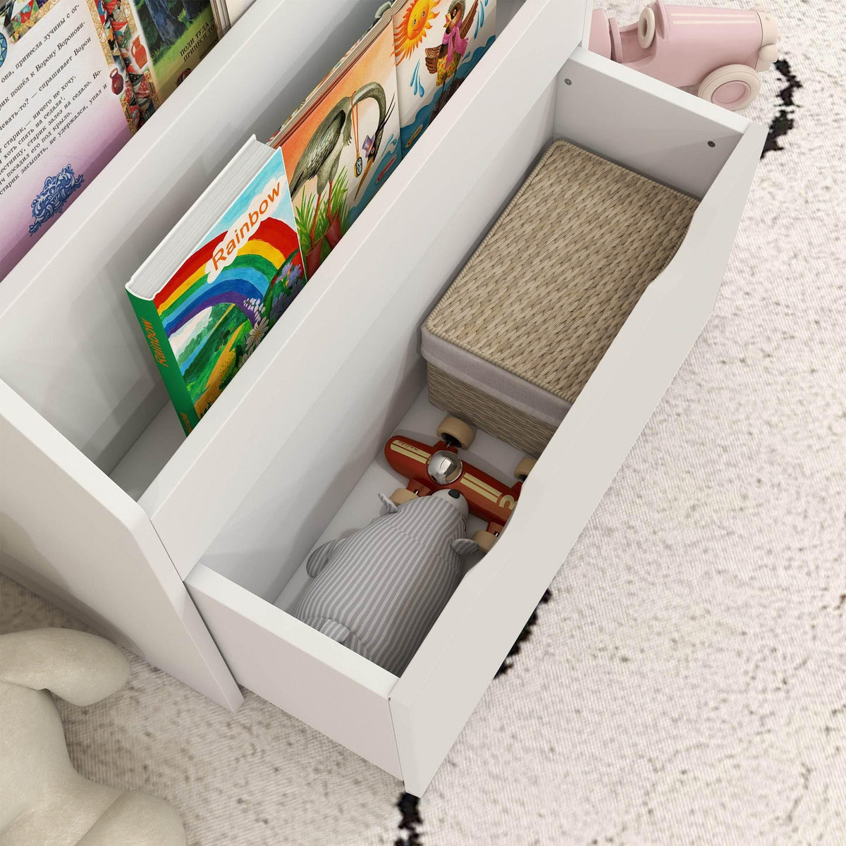White bookcase with open drawer compartment filled with children’s books