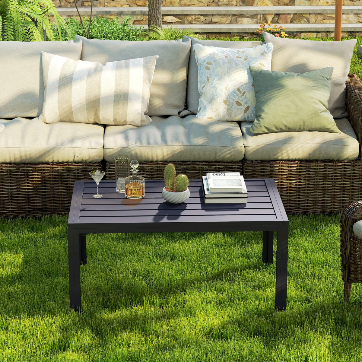 Rectangular outdoor side table with slatted dark grey tabletop and four legs on grass