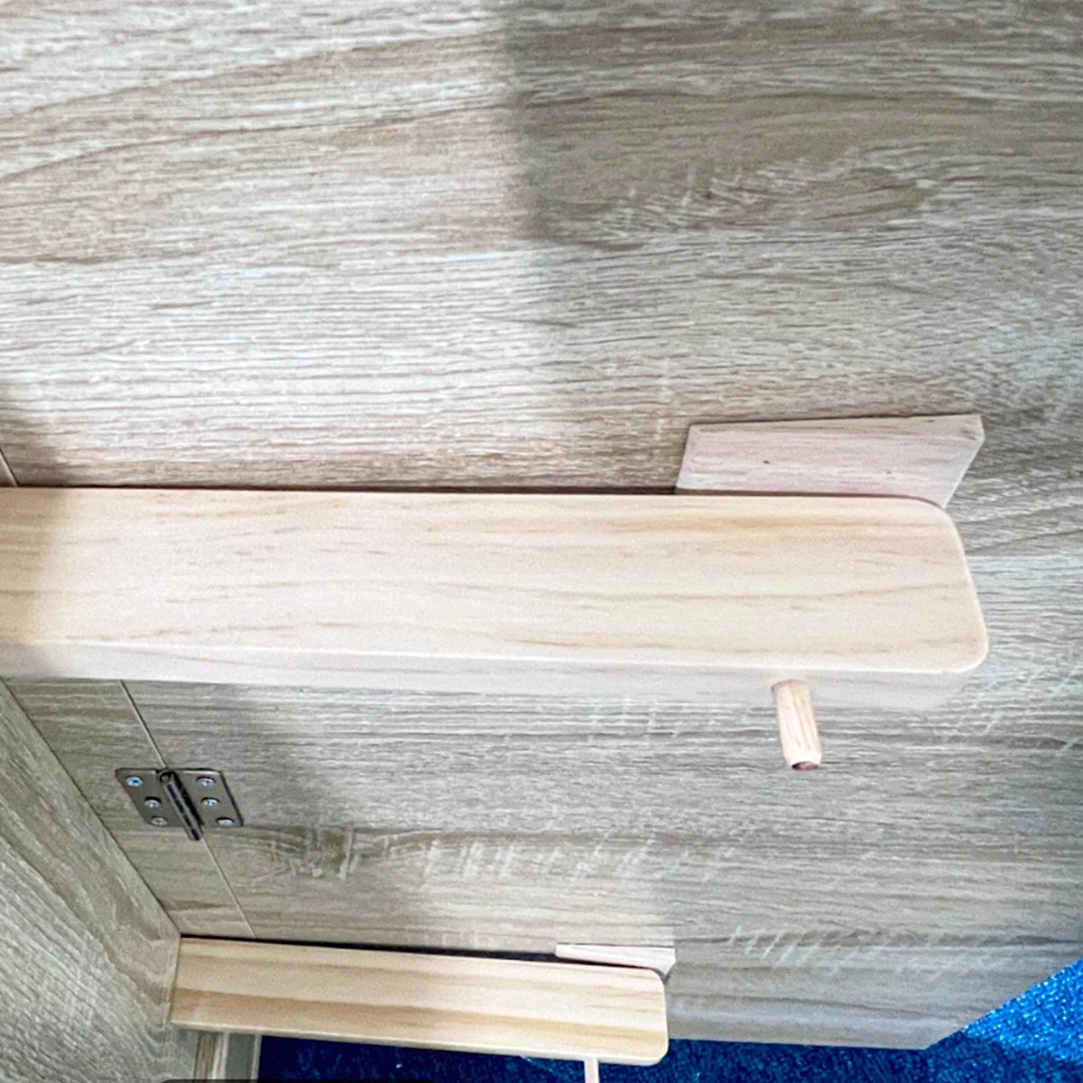 Underside view of light oak drop-leaf tabletop with metal hinge hardware and supports