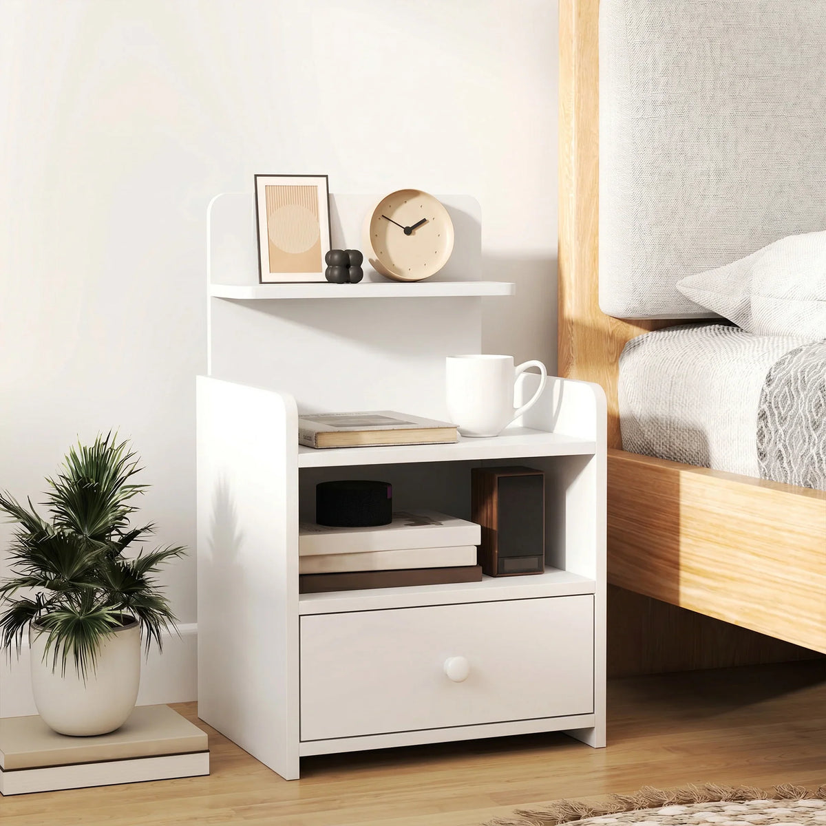 White bedside cabinet with open shelf spaces and a bottom drawer with knob