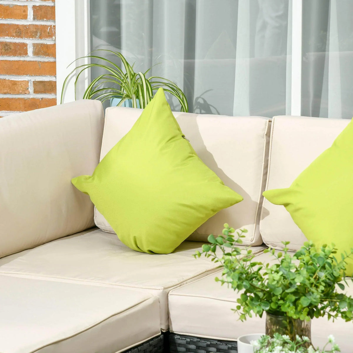 Cream outdoor sofa cushions with lime green pillows on black rattan seats