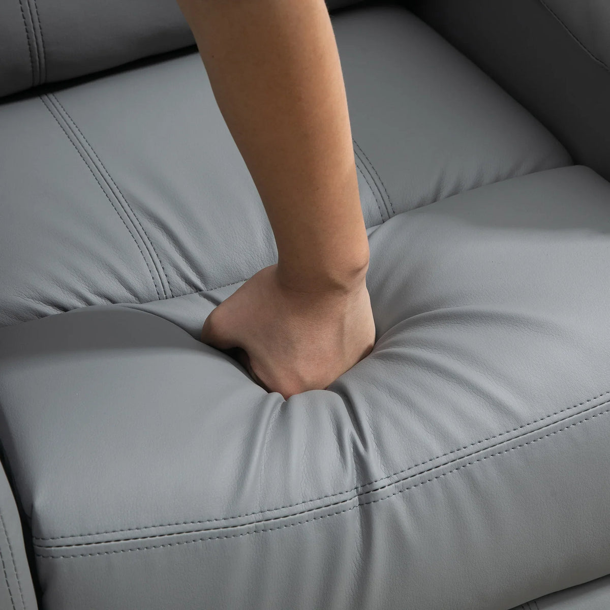 Grey cushioned recliner seat with stitched seams and foot resting on comfort platform