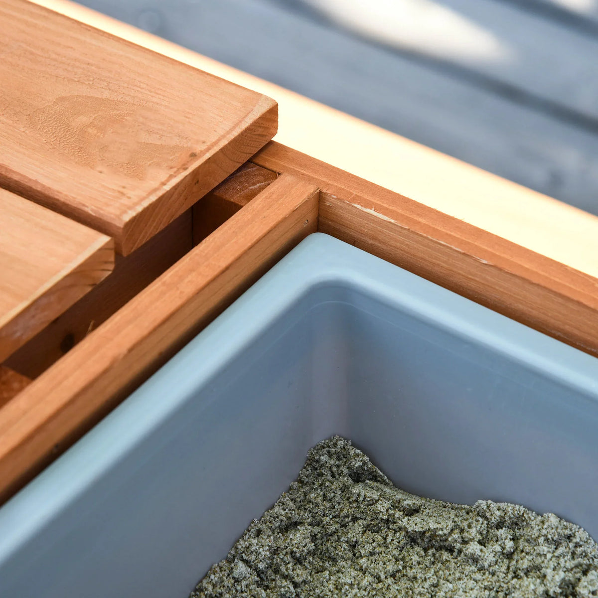 Brown wooden frame with light-blue water or sandbox bin insert, close-up