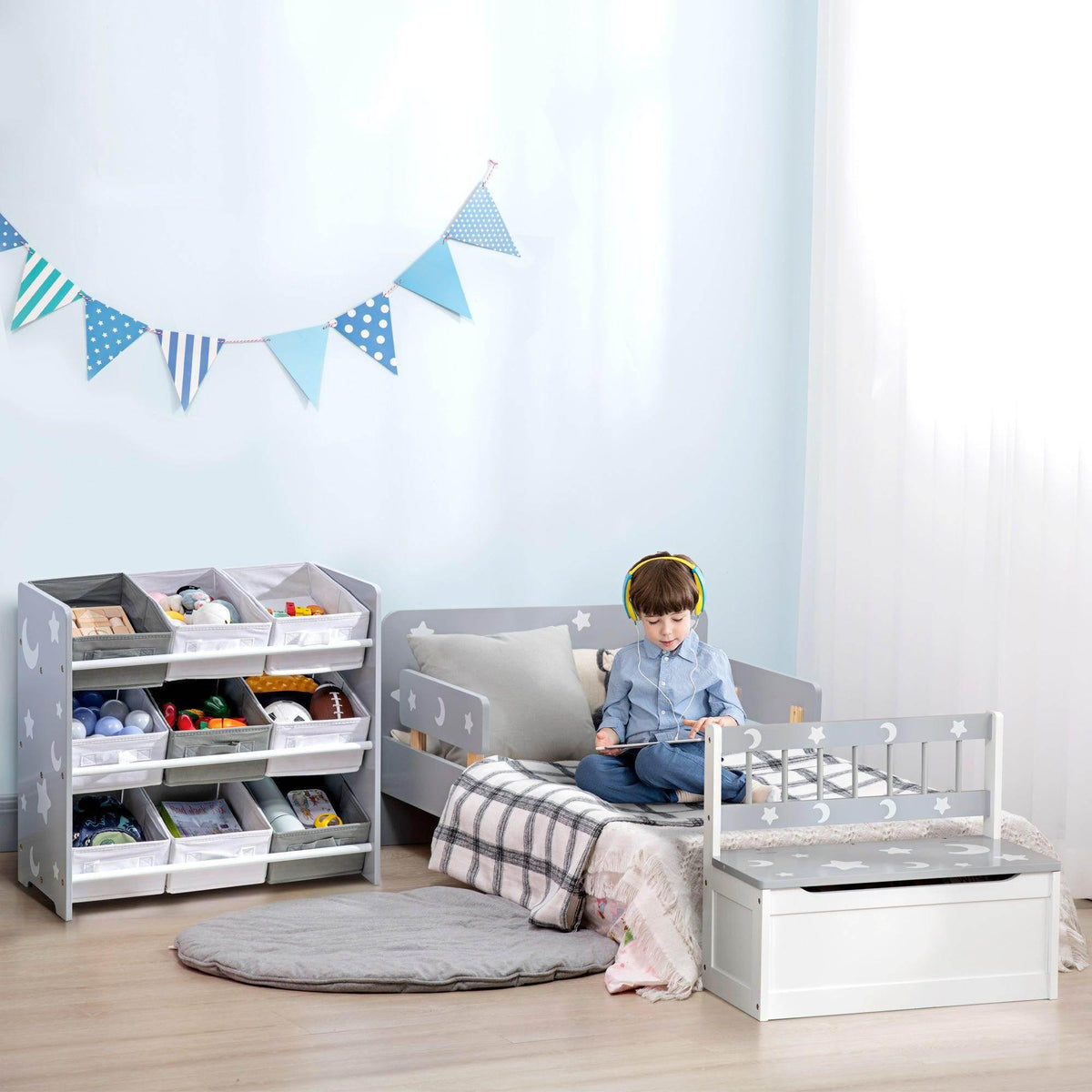 Gray storage unit with 9 baskets and a kid play bed with side guard rails