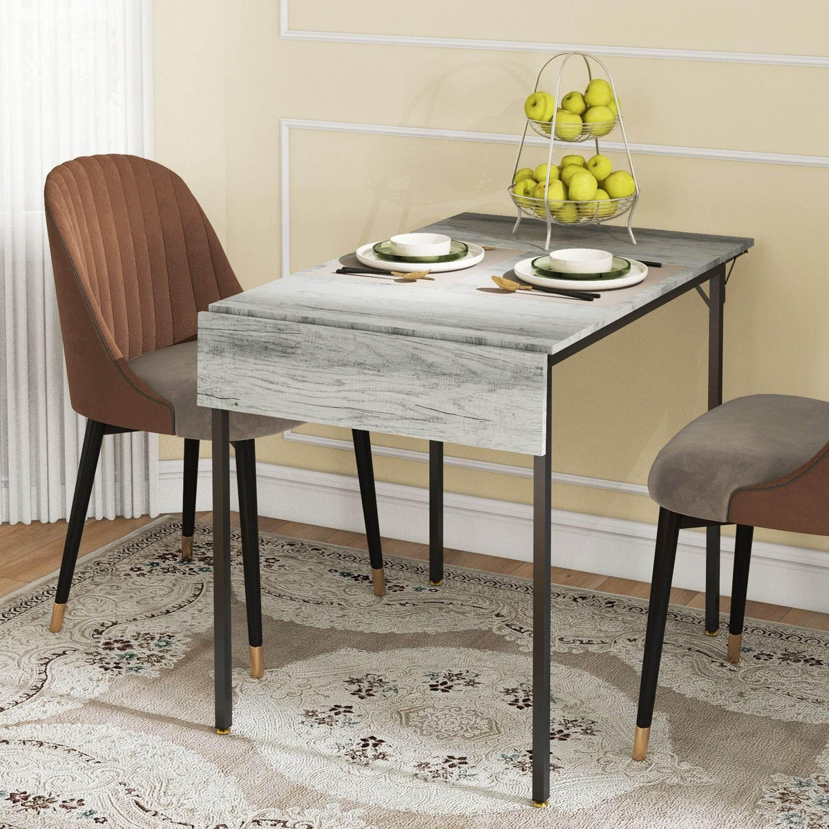 Grey drop-leaf folding dining table with black legs and upholstered chairs