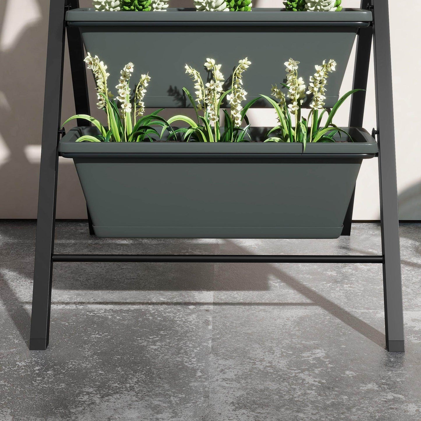 Close-up of grey raised top planter box with green seedlings and small flowers