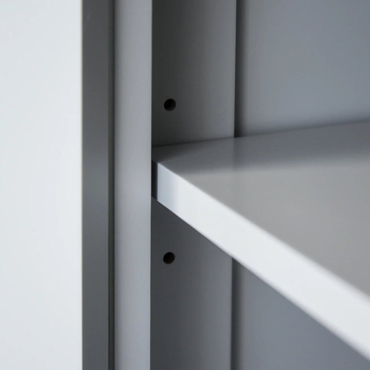 Close-up of grey pantry cabinet shelf support holes and inner shelf edge
