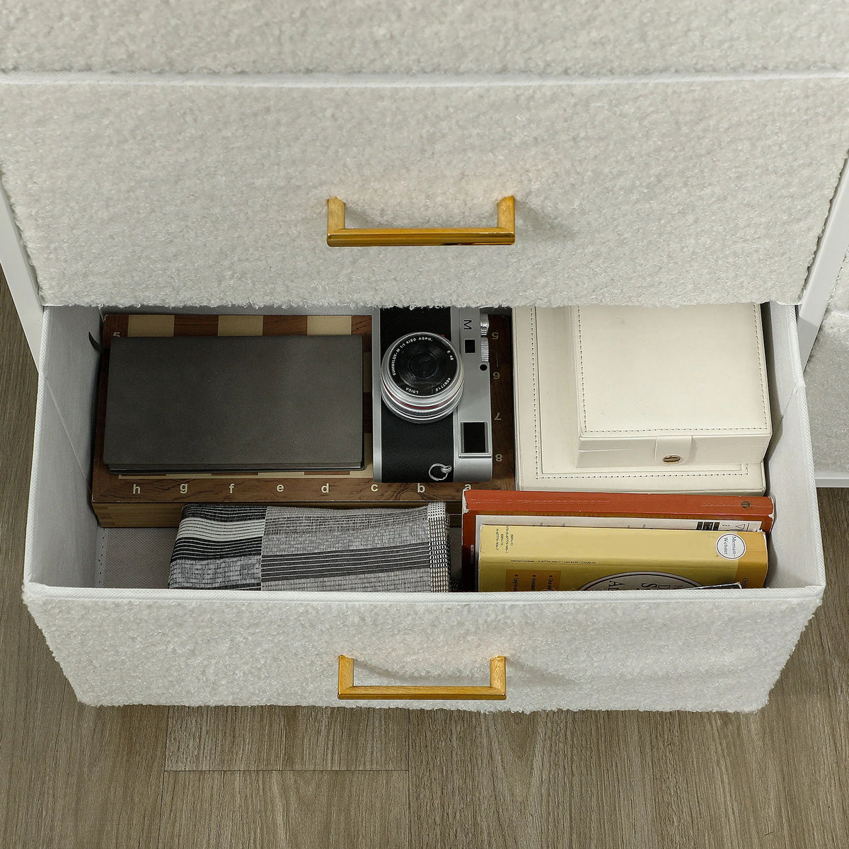 Open fabric drawer inside a cream white boucle chest of drawers with gold handle