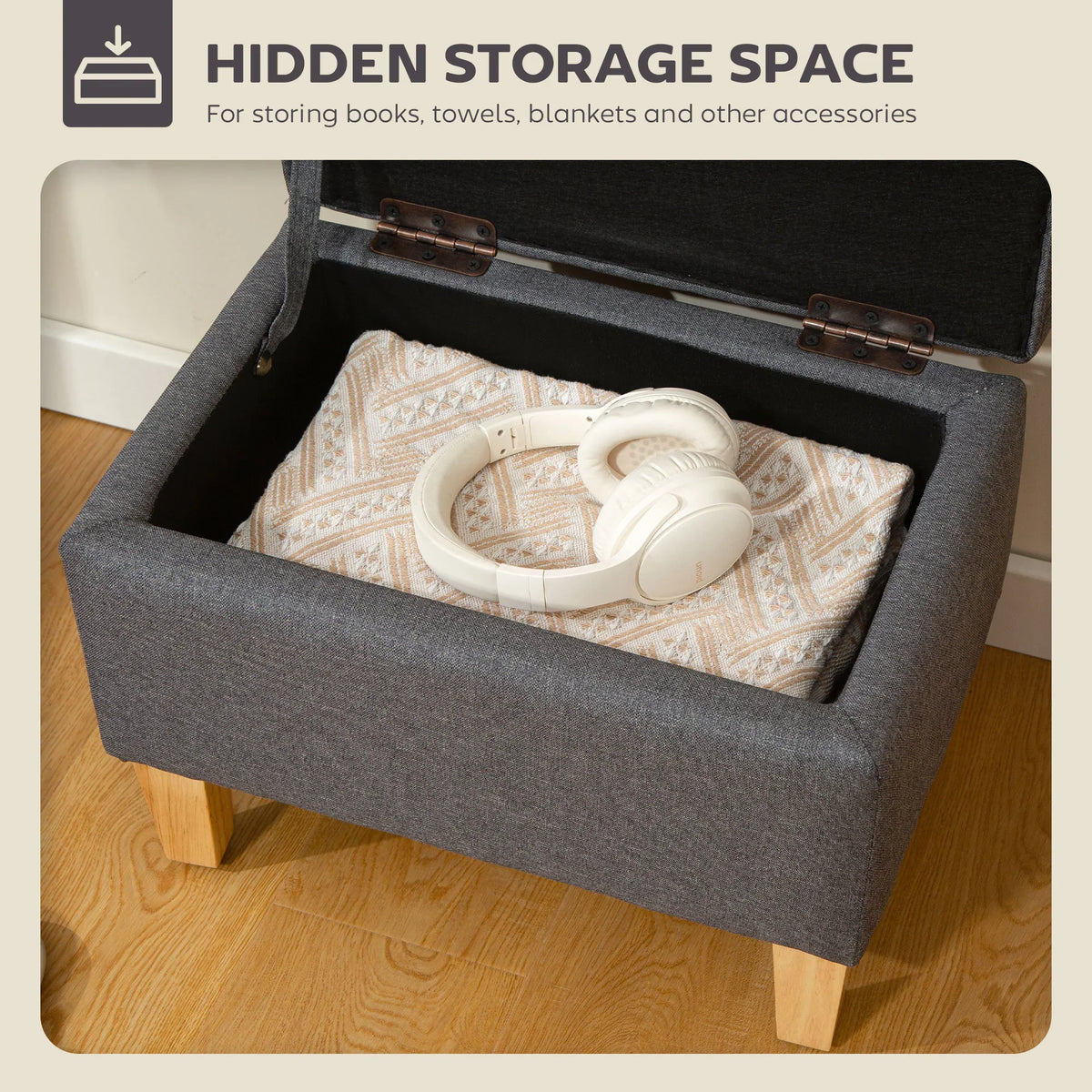 Charcoal grey storage ottoman open to reveal a padded compartment with contents
