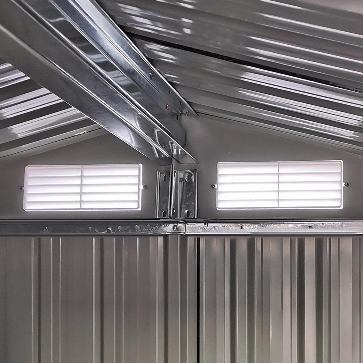 Interior view of green metal storage shed with vented panels and roof support beams