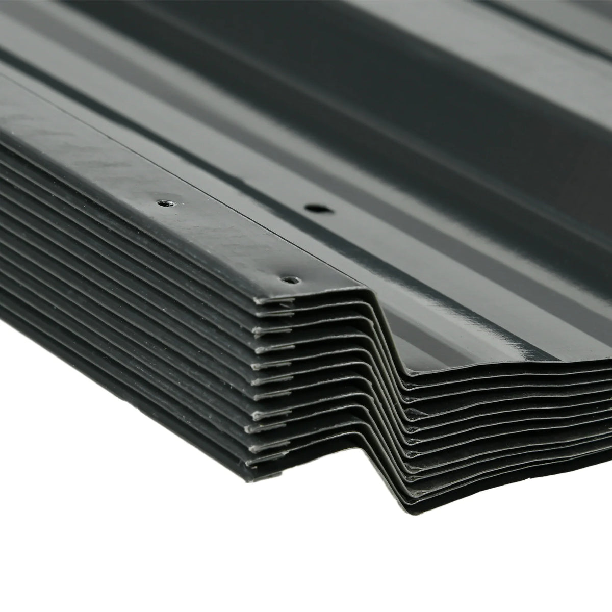 Stack of dark grey corrugated roofing sheets with overlapping edges and fixing holes