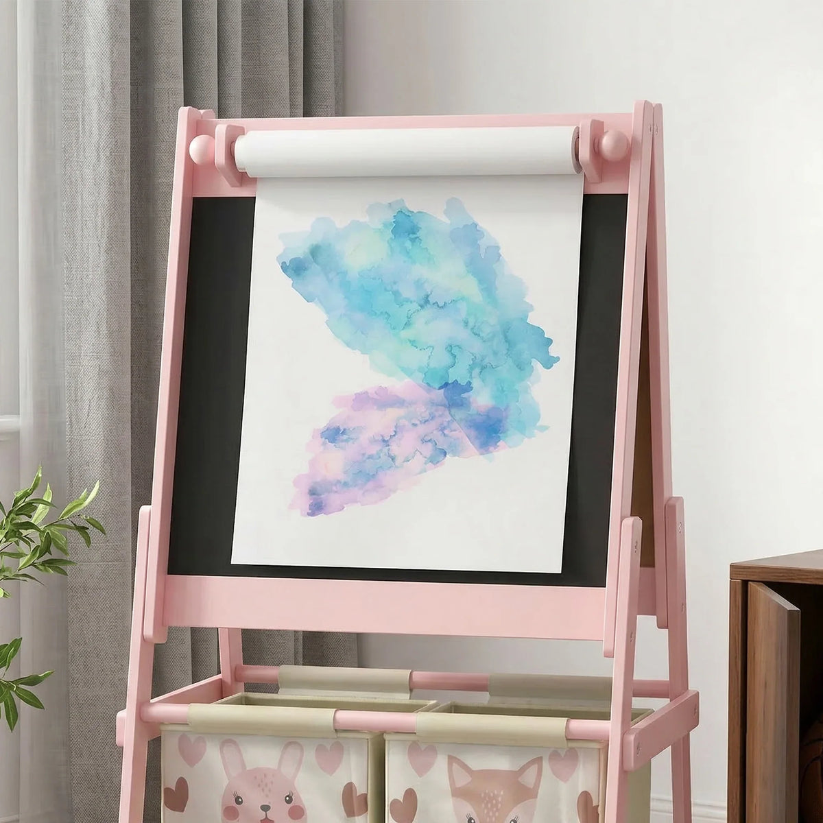Pink kids easel with blackboard panel and white paper roll above