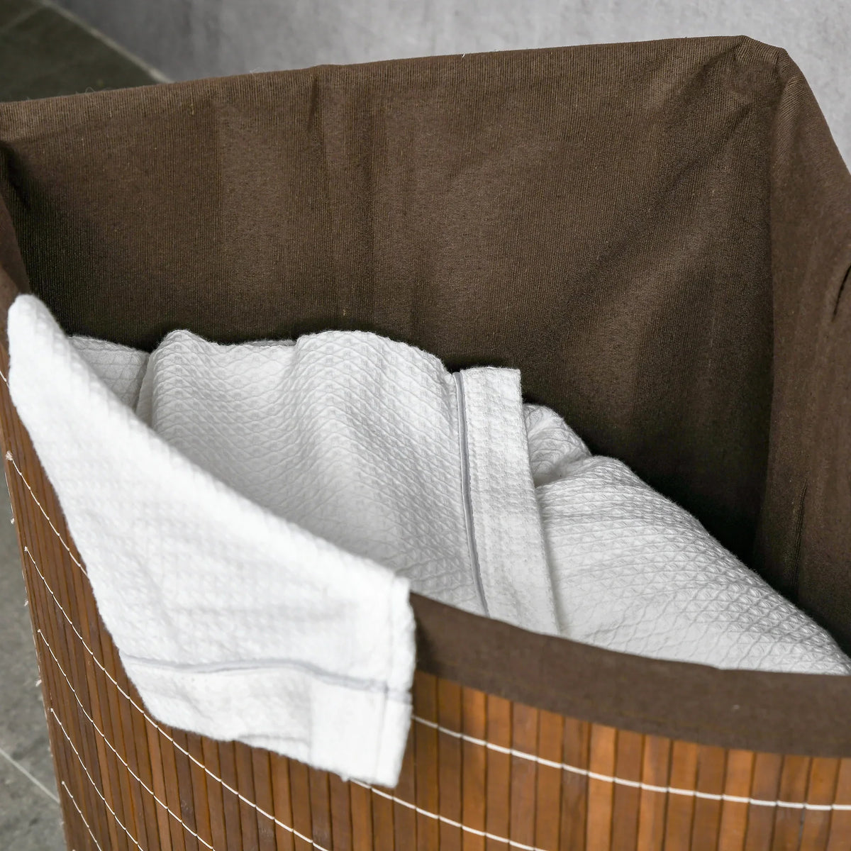 Brown bamboo laundry hamper with removable liner bag holding folded towels