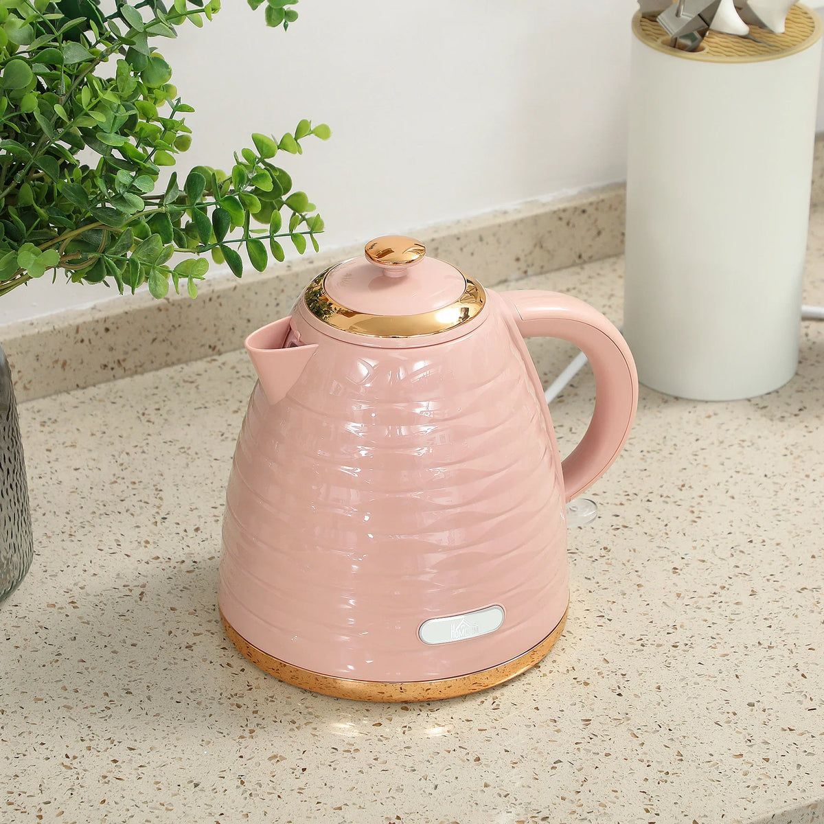 Pink electric kettle with gold lid, curved handle, and honeycomb-style body on countertop