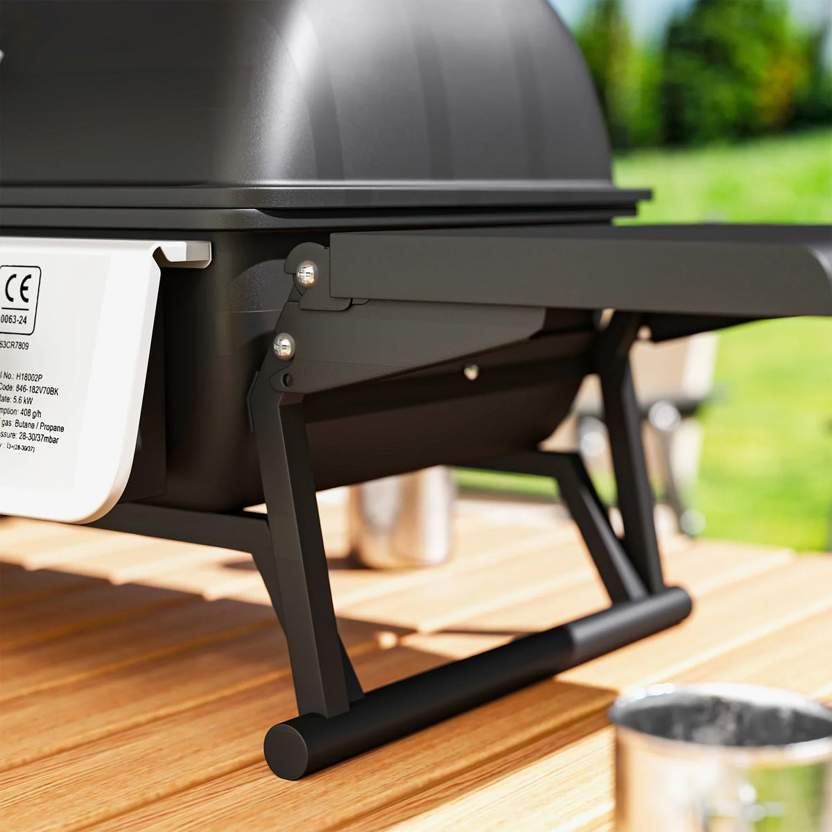 Black gas grill stand with support legs under the closed lid