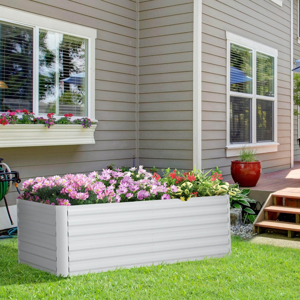 Light grey galvanized steel outdoor raised bed with ribbed sides, planted with flowers