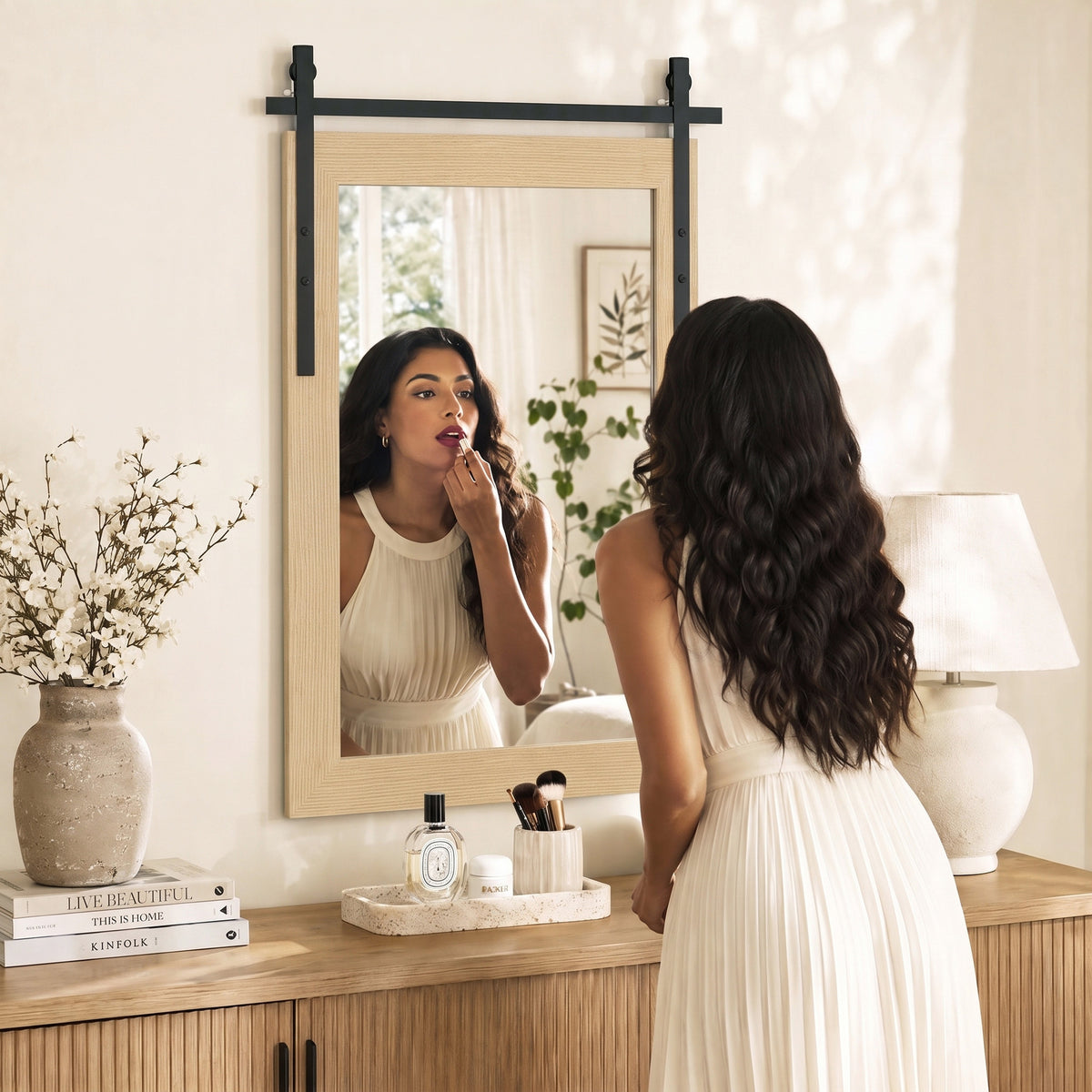 Rectangular wall mirror with wood-look frame reflecting a person in a room