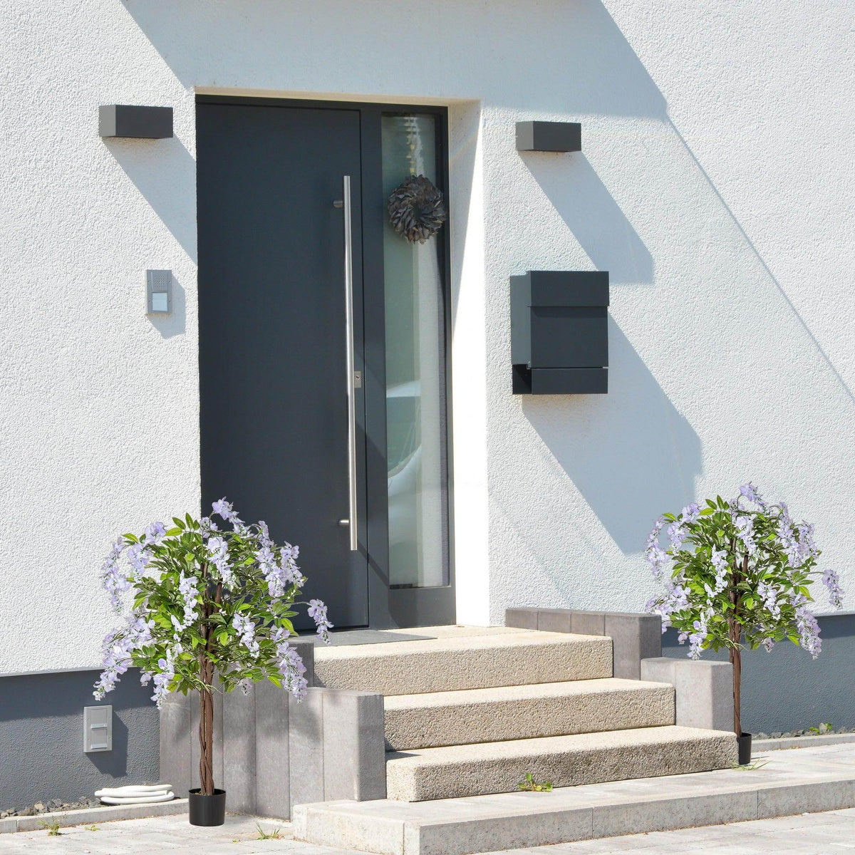 Set of 2 artificial wisteria plants in dark pots with lilac and white blooms and green leaves
