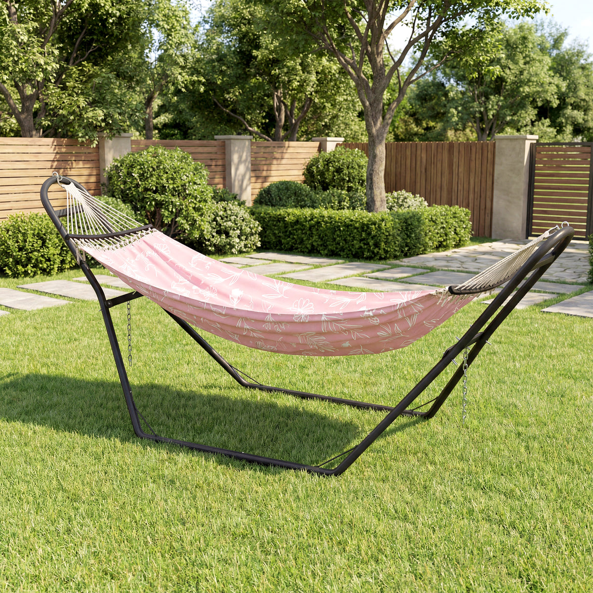 Black hammock stand with pink hammock fabric in an outdoor garden yard