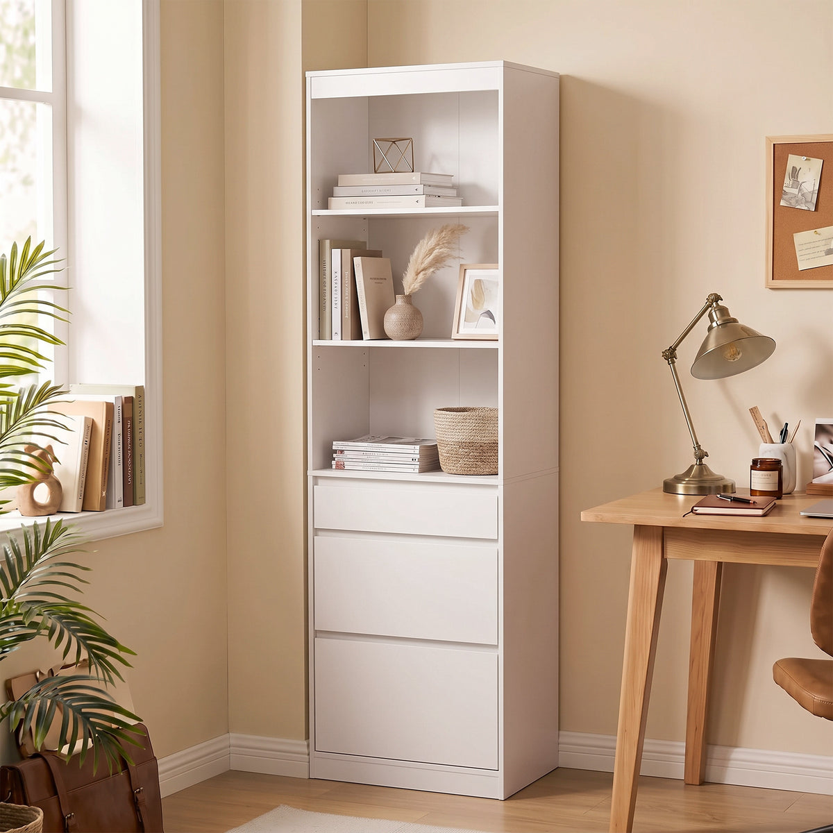White tall bookcase with open shelving and three drawers stacked at the bottom.