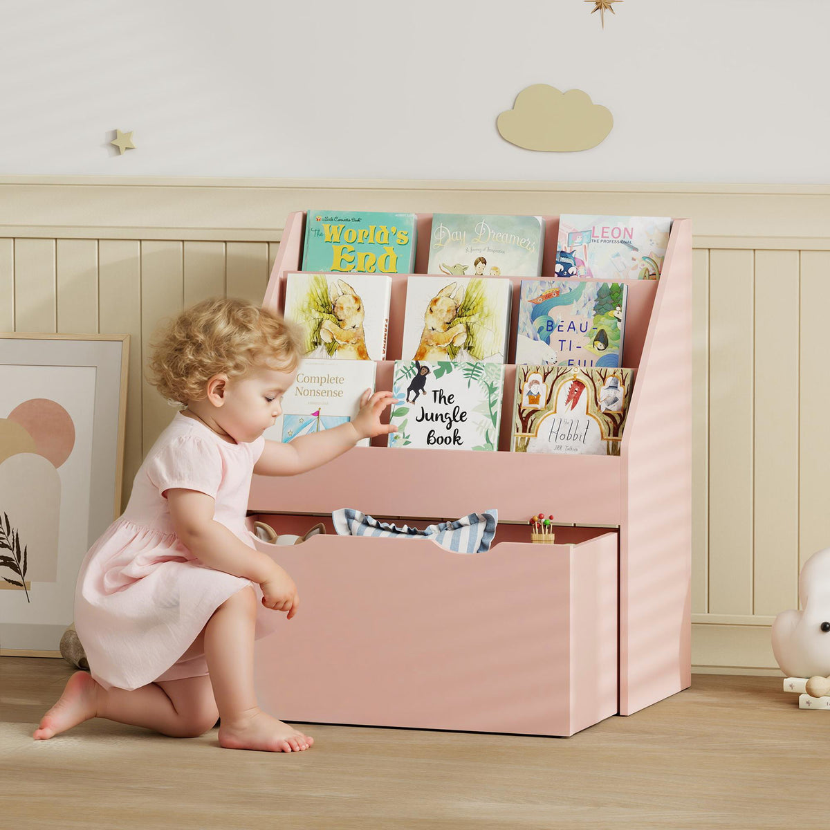 Pink kids bookcase with three shelves and wheeled drawer holding children’s books