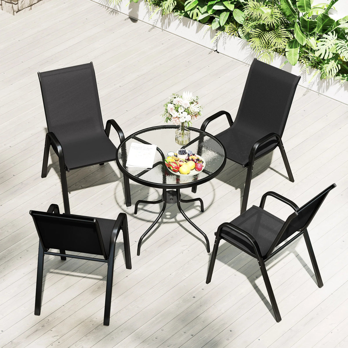 Black stackable patio chairs around round glass-top table on outdoor deck