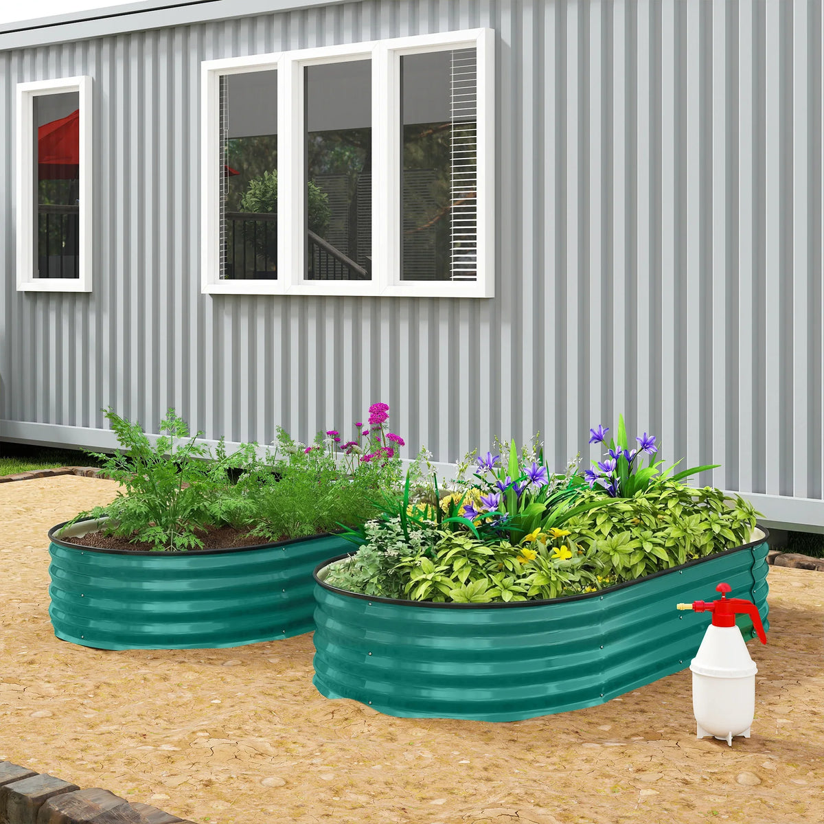 Green raised garden bed set on ground with two planters of herbs and flowers in view.