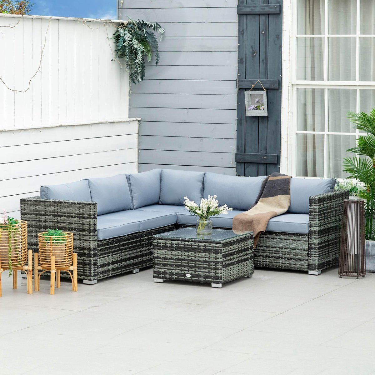 Grey outdoor rattan sofa set with corner chaise, matching cushions, and glass coffee table