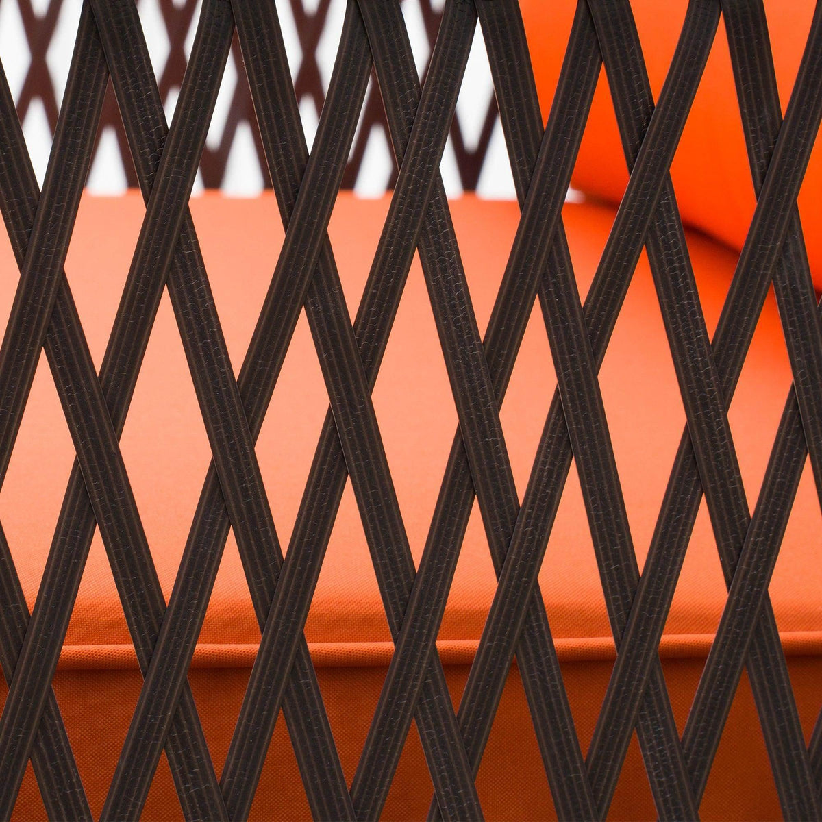 Close-up of dark brown woven rattan pattern over an orange seat cushion
