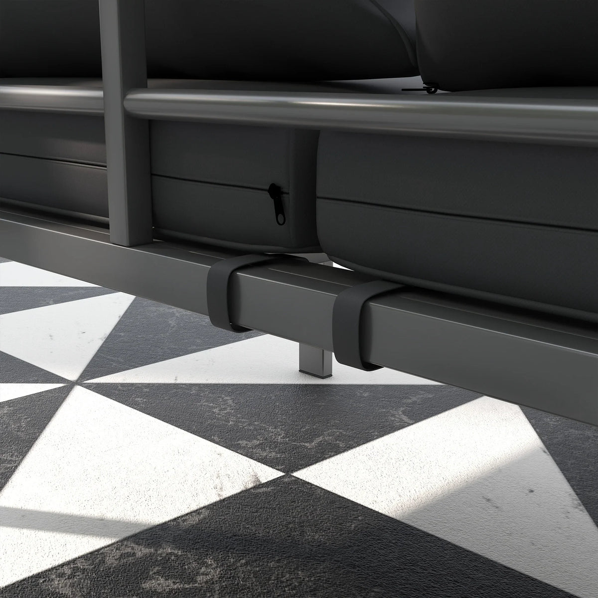 Grey outdoor bench with padded cushions and front support bar above patio tiles