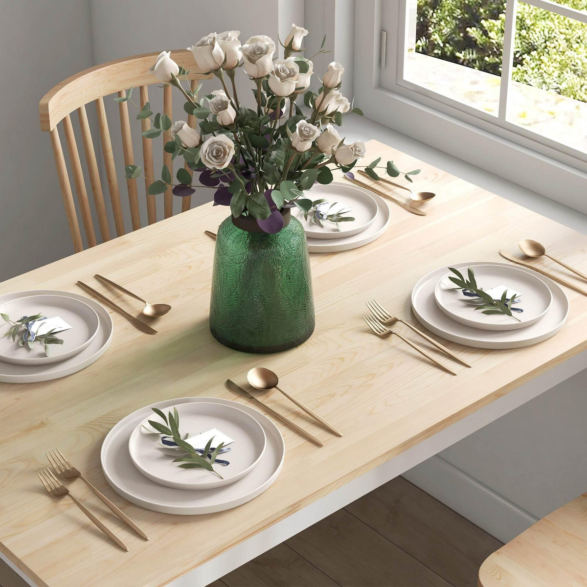 Close-up of light pine dining table with white place settings and cutlery