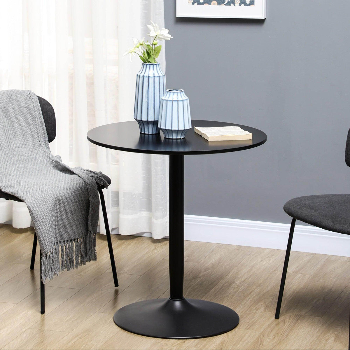 Black round dining table with smooth tabletop and steel pedestal base