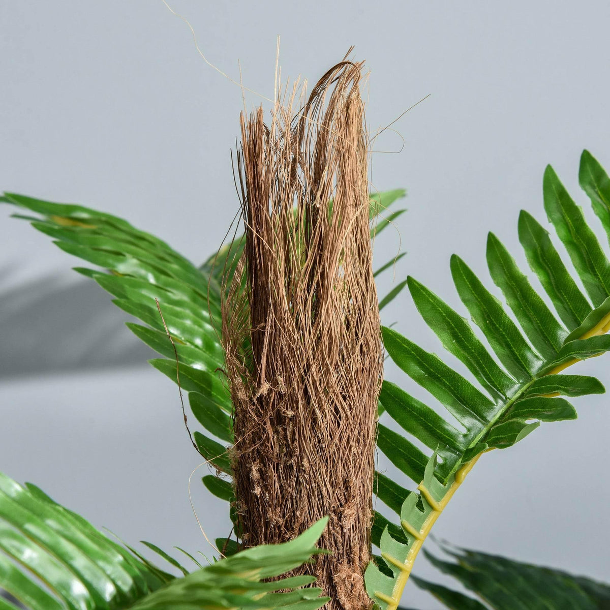 Close-up of artificial palm trunk with textured brown fibers and green fronds