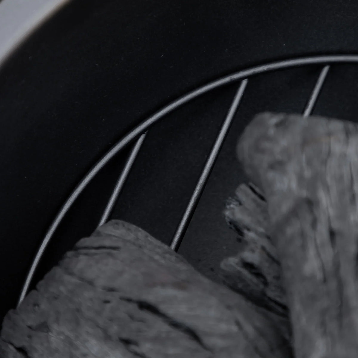 Close-up of fire pit interior with charcoal logs and curved black rim