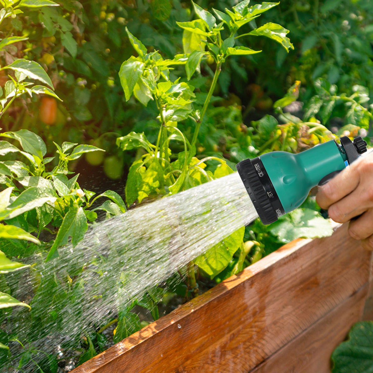 Green hose nozzle spraying water stream for garden watering